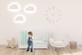 Boy in kidÃ¢â¬â¢s room with clocks, white walls